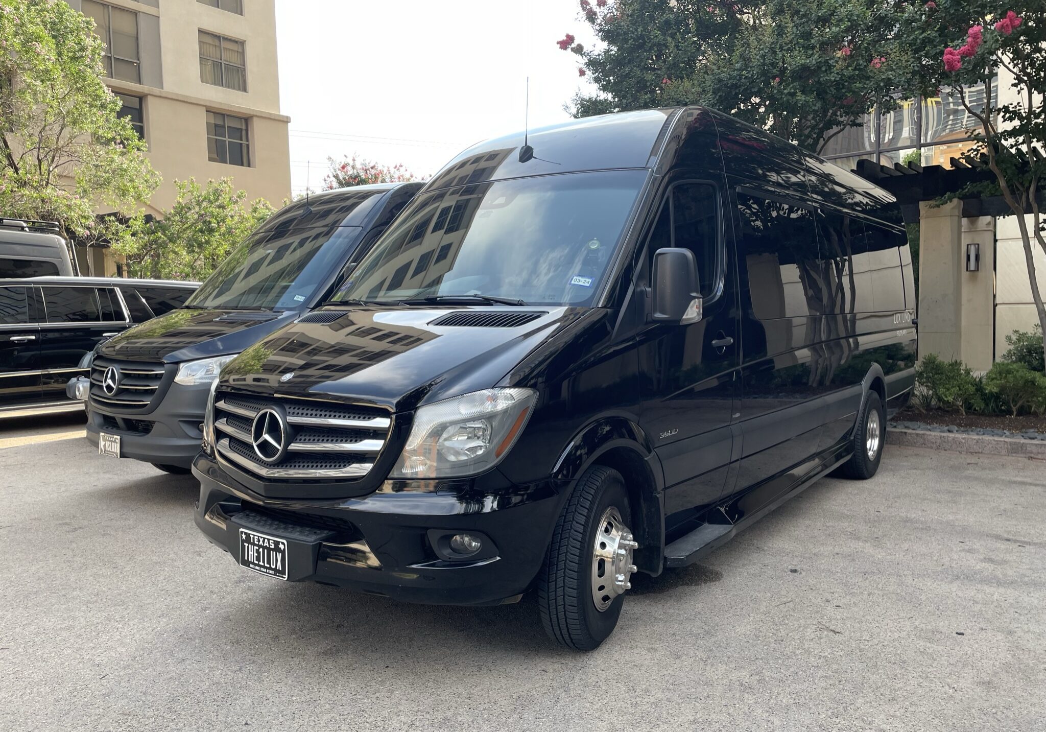 Sprinter parked at four seasons hotel Limo Service Pflugerville Black Mercedes sprinter van "lux limo" logo on the side of the van near the rear